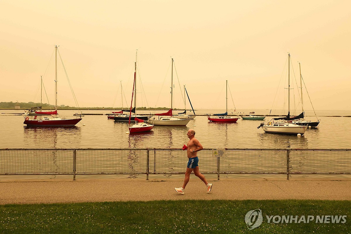 캐나다 온타리오주 북서부에서 발생한 산불 연기가 대도시로 대량 유입되면서 공기질이 악화된 가운데, 한 시민이 토론토의 해안가를 따라 달리고 있다. 사진=AFP·연합뉴스