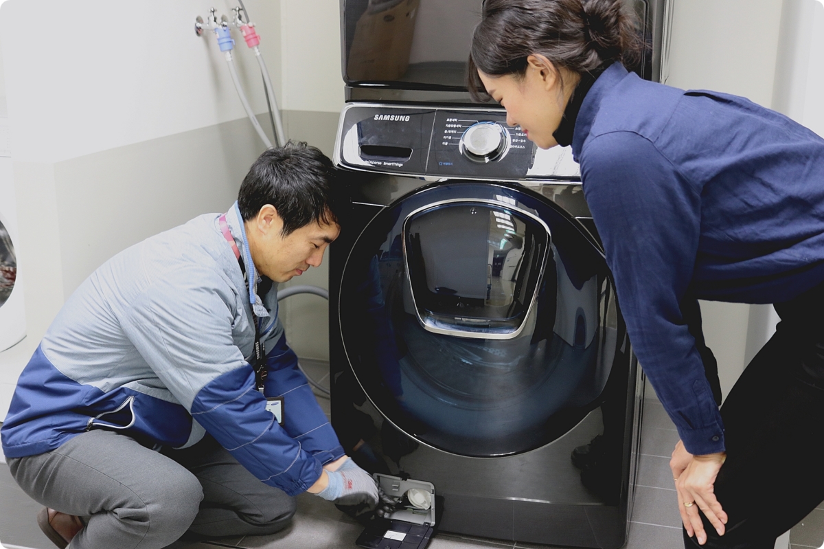 삼성전자서비스 수리 엔지니어가 출장 점검 서비스를 신청한 고객에게 플러스 원 케어 서비스의 일환으로 드럼세탁기 배수펌프 잔수 제거 방법을 설명하고 있다.