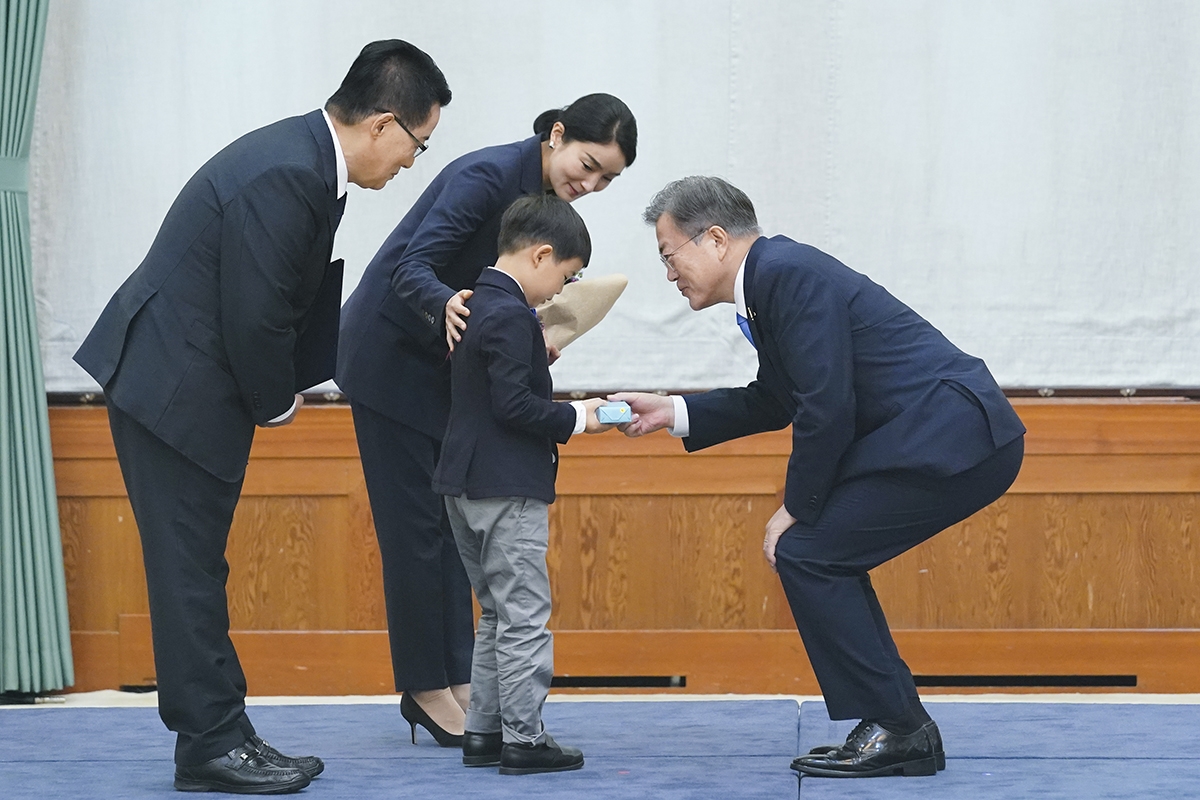 문 대통령이 수여식에 참석한 박지원 국정원장 손자에 기념품을 전달하고 있다(청와대 제공)